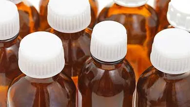 Close-up of several amber glass bottles with white, ribbed caps.